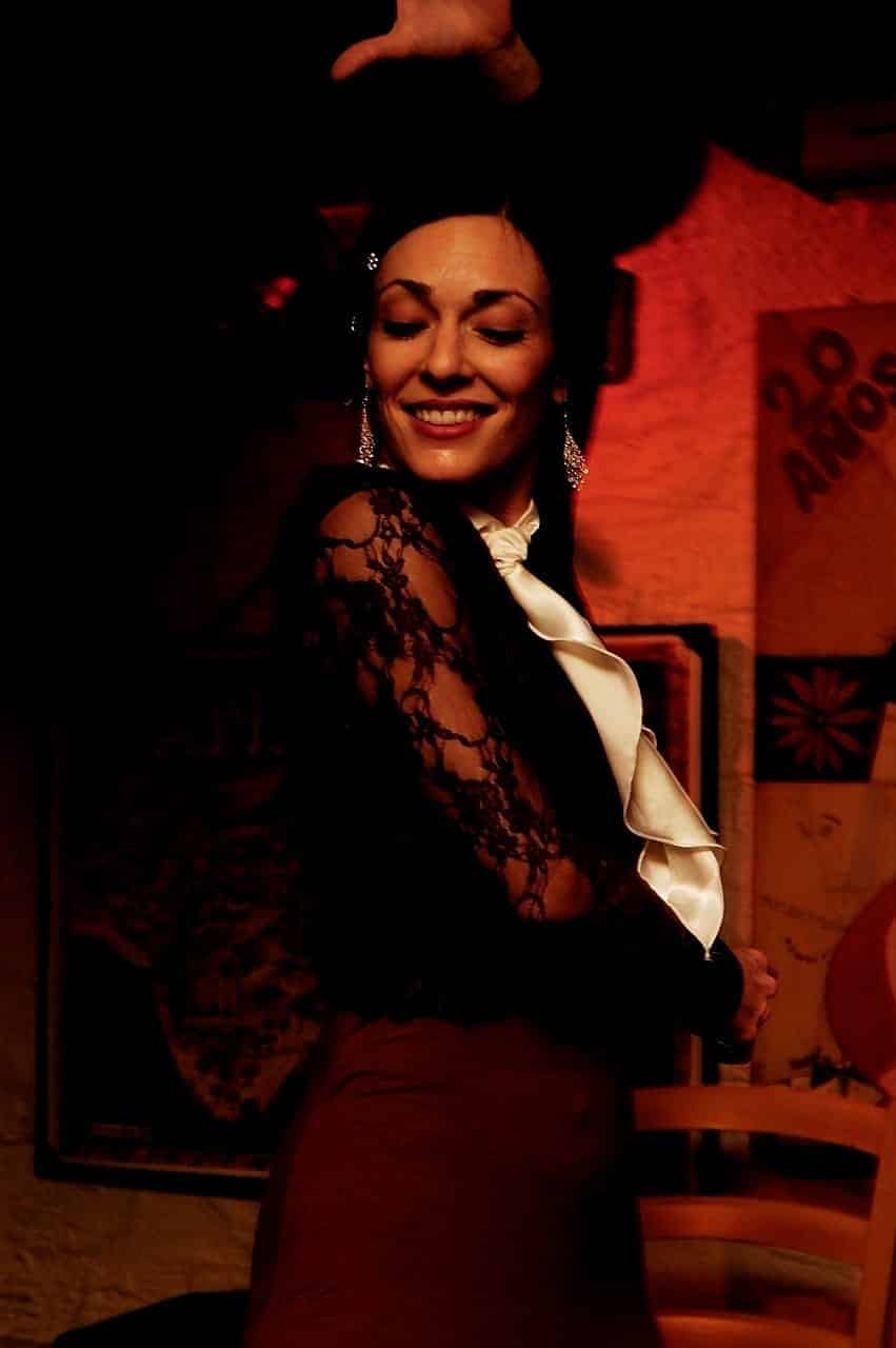 Bailaora sonriendo con los ojos cerrados, con blusa de encaje negra y chorrera clara